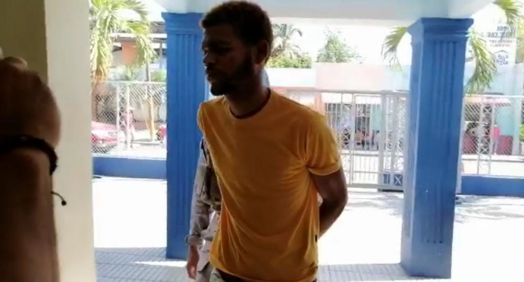 Momentos en que agentes policiales llevaban detenido al joven que intentó incendiar la casa de su madre en La Vega.