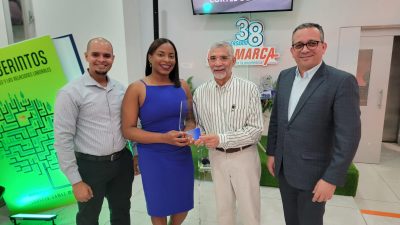 Yuberkis Guante, conductora del programa y encargada de prensa de la Fiscalía del Distrito Nacional, junto a algunos fiscales y abogados, mientras reciben la placa de mano del presidente de la empresa Logomarca, Lorenzo Gómez Marín